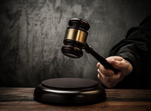 Close up of a judge's hand positioning a gavel above a sound block.