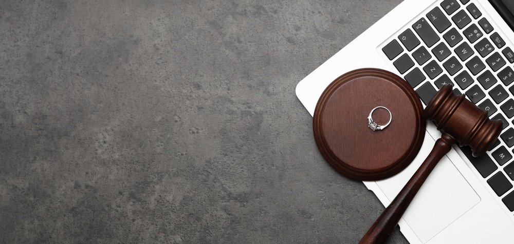 Wedding ring and judge's gavel resting on a laptop keyboard symbolizing digital assets in divorce