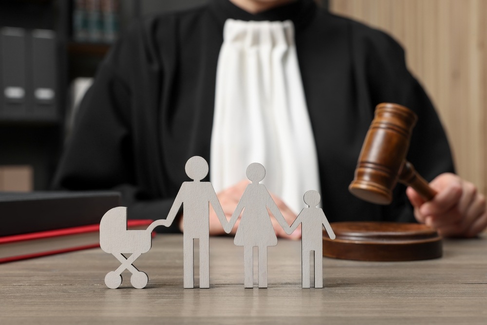 Judge holding gavel behind wooden family figures symbolizing parental rights case