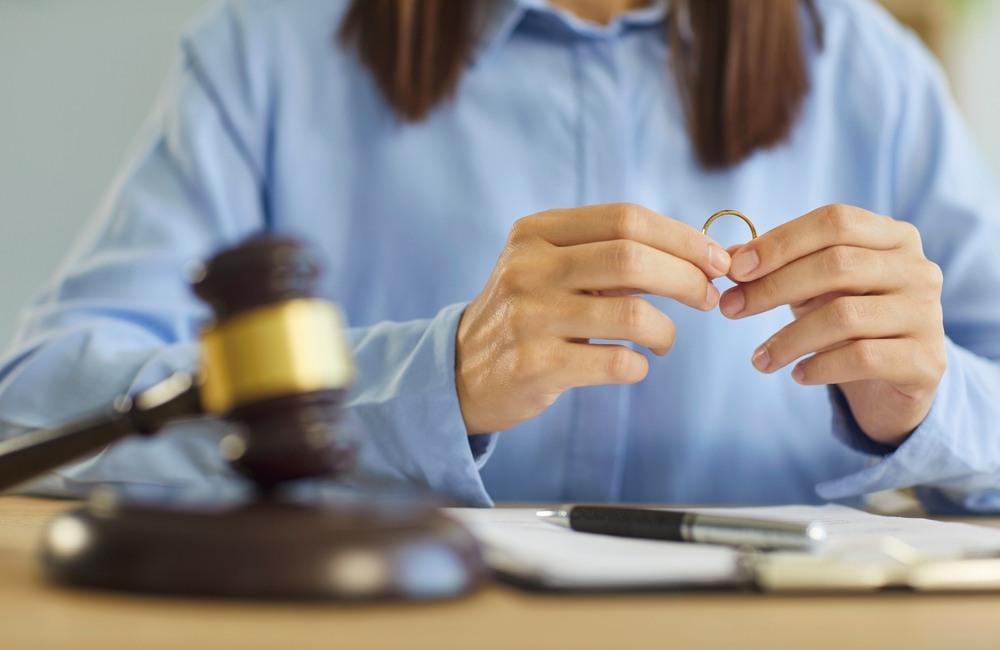 A client holding a gold wedding ring over legal paperwork next to a judge's gavel during a legal separation consultation with a San Francisco family law attorney.